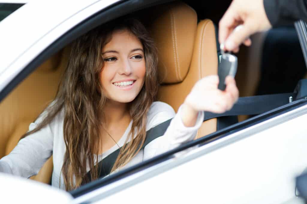 young woman in car receiving keys